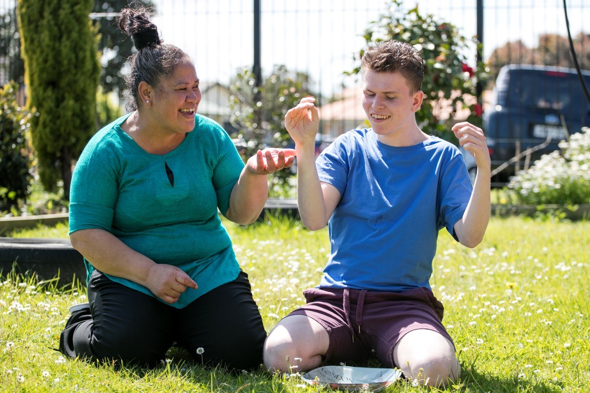 Youth with caregiver kneeling on grass